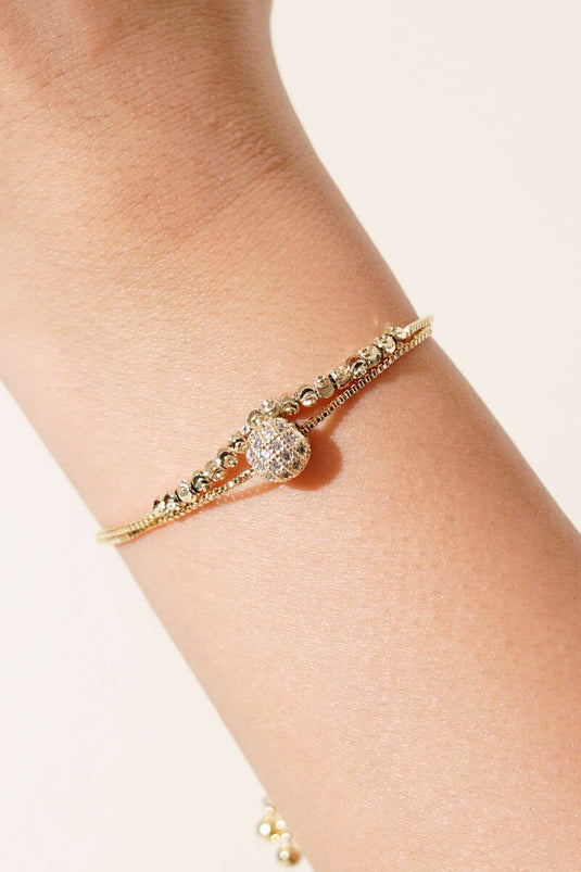 Pulsera dorada con detalles de piedras y bola