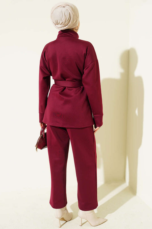 Combinaison deux pièces bordeaux en néoprène, cintrée à la taille et ceinturée.