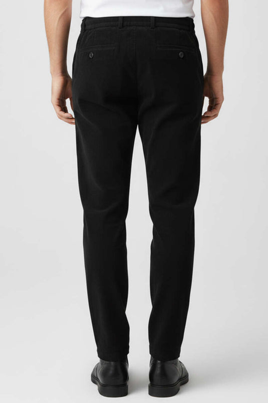 Pantalon en velours noir avec taille élastiquée à cordon.