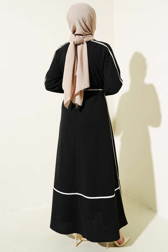 Schwarzes Kleid mit floralem Accessoire und Paspelierung