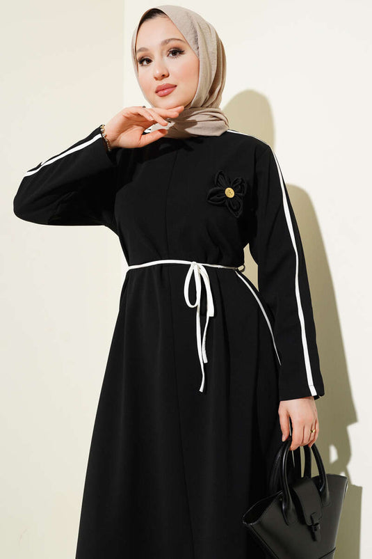 Schwarzes Kleid mit floralem Accessoire und Paspelierung