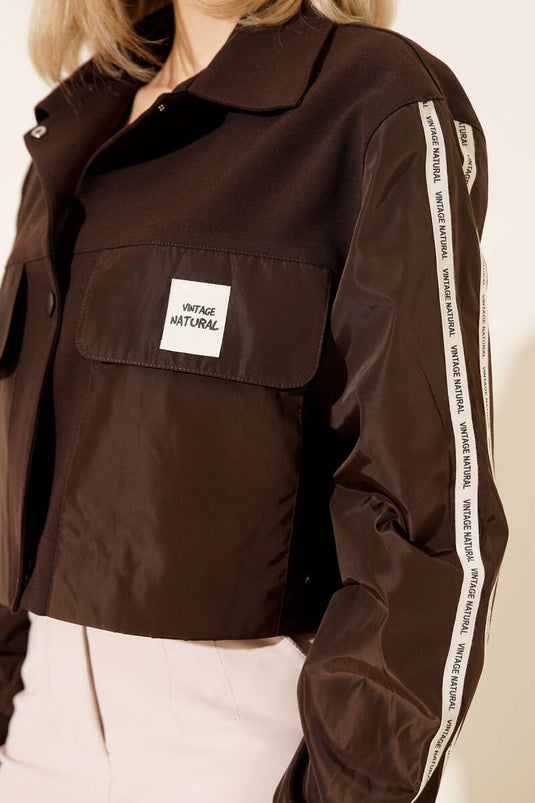 سترة بجيوب مع شريط مكتوب باللون البني