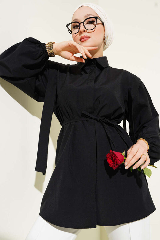 قميص أسود بأكمام طويلة وحزام على الكتف