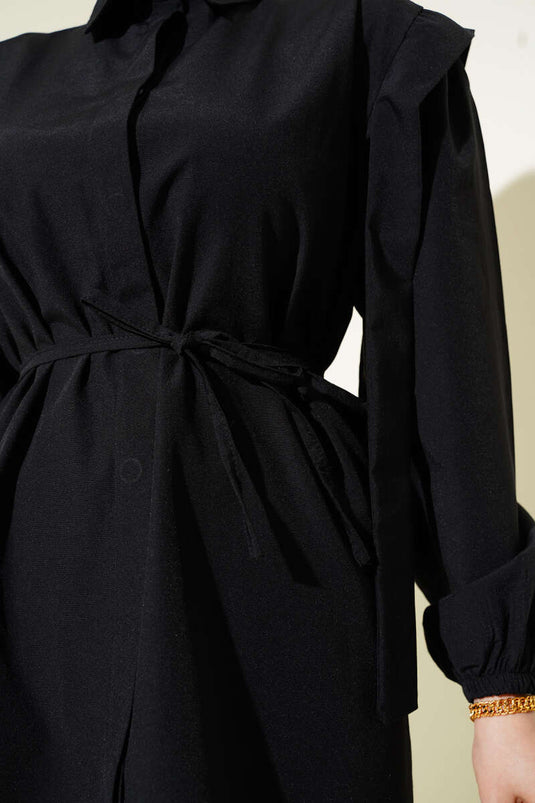 قميص أسود بأكمام طويلة وحزام على الكتف