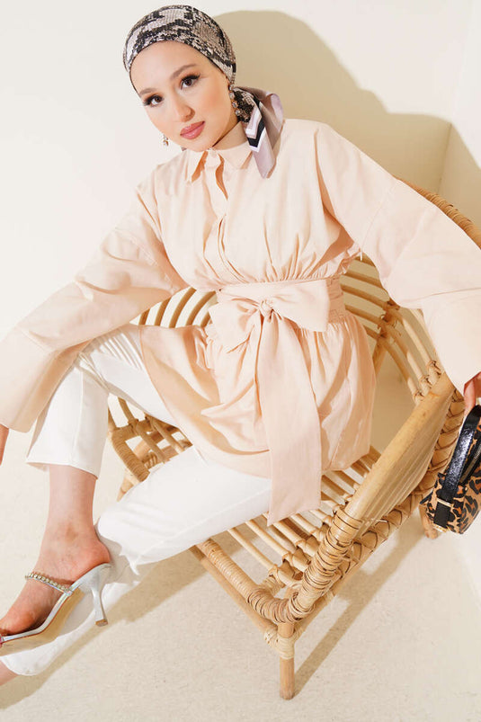 Tunique beige à ceinture intégrée et froncée sur le devant.