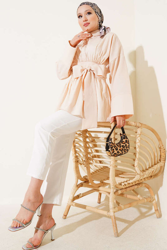 Tunique beige à ceinture intégrée et froncée sur le devant.