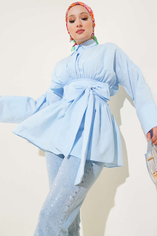 Tunique bleue à ceinture intégrée et froncée sur le devant.