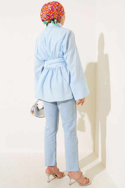 Tunique bleue à ceinture intégrée et froncée sur le devant.