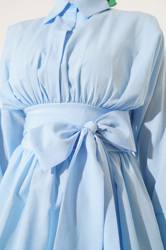 Tunique bleue à ceinture intégrée et froncée sur le devant.