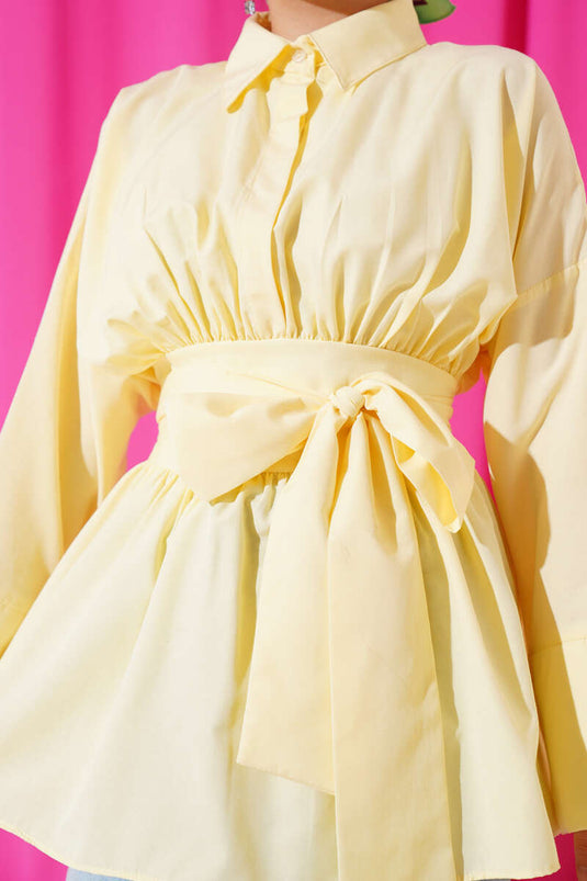 Tunique jaune à ceinture intégrée et froncée sur le devant.