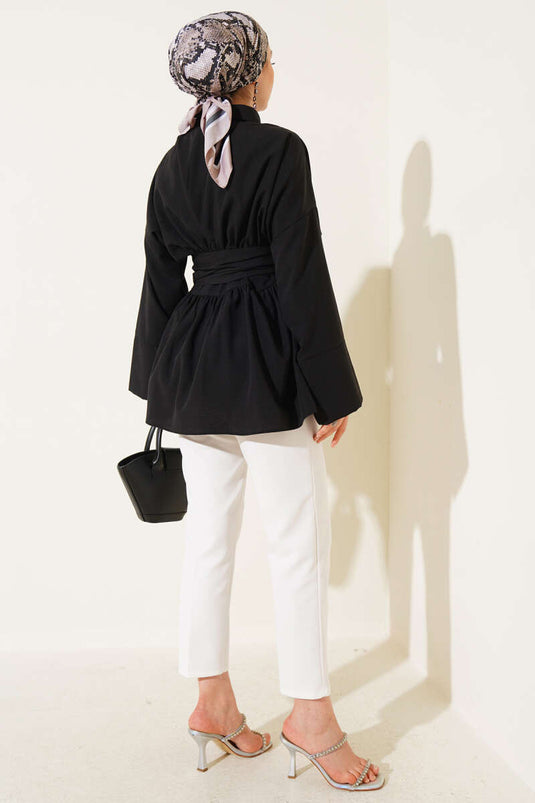 Tunique noire à ceinture intégrée et froncée sur le devant.