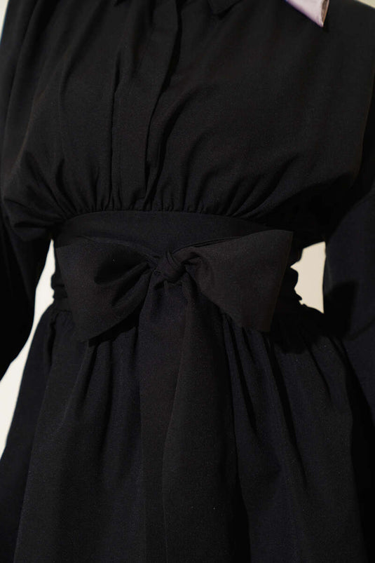 Tunique noire à ceinture intégrée et froncée sur le devant.