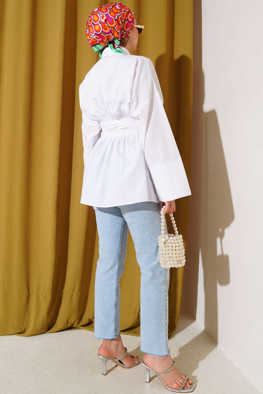 Tunique blanche à ceinture intégrée et froncée sur le devant.