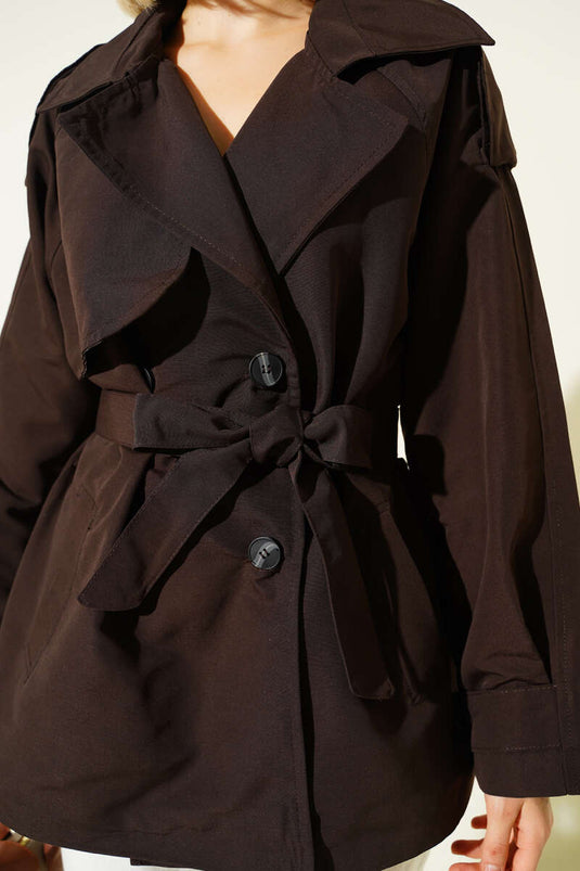 معطف قصير بني اللون، ذو صفين من الأزرار وحزام.