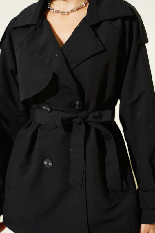 معطف قصير أسود اللون، ذو صفين من الأزرار وحزام.