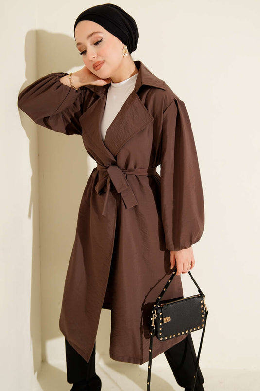 Trench-coat marron à double boutonnage, manches bouffantes et ceinture.