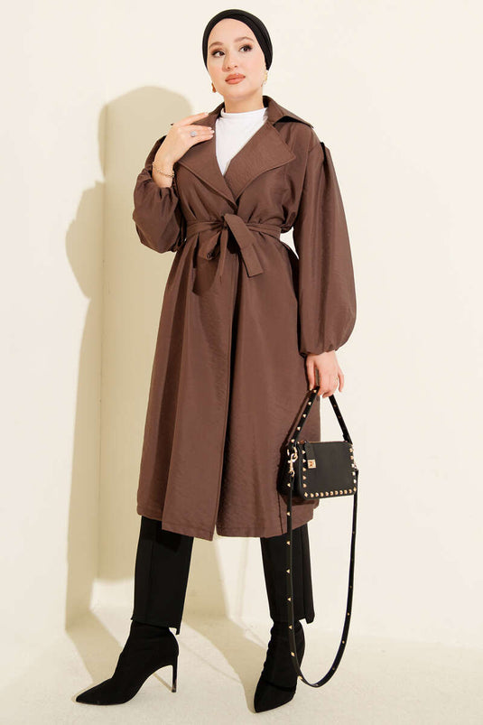 Trench-coat marron à double boutonnage, manches bouffantes et ceinture.