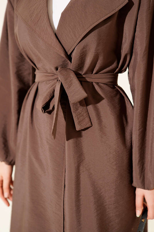 Trench-coat marron à double boutonnage, manches bouffantes et ceinture.