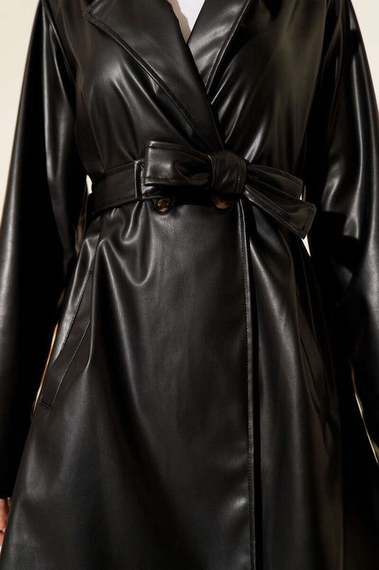 Trench-coat court en cuir noir, croisé et ceinturé.