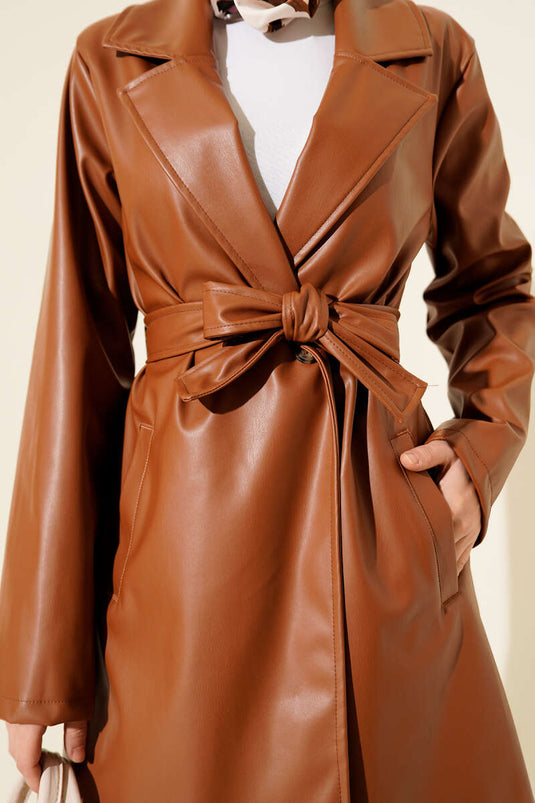 Trench-coat court en cuir beige à double boutonnage et ceinture.