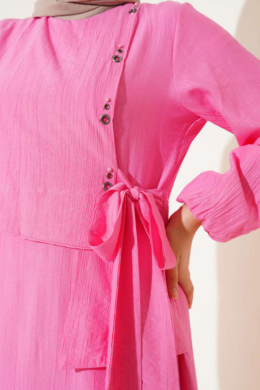 فستان وردي بربطة عنق وتفاصيل فتحات