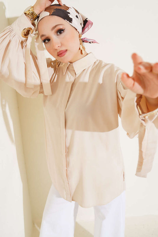 قميص بأكمام منفوخة وتفاصيل فتحات صغيرة باللون البيج