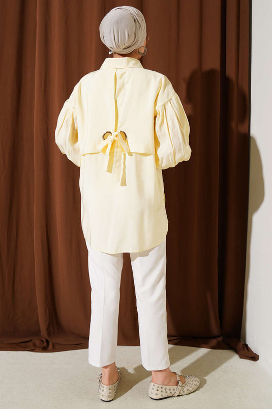 قميص أصفر بأكمام منفوخة وتفاصيل فتحات