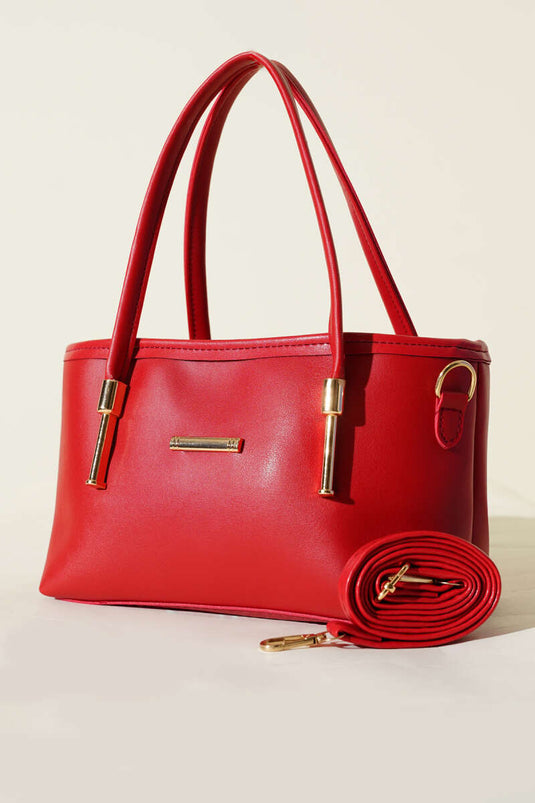 حقيبة يد حمراء مزينة بشعار معدني