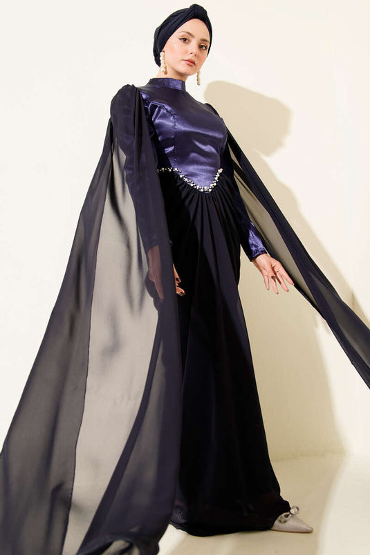 Marineblauwe avondjurk met schoudercape en details van steentjes.