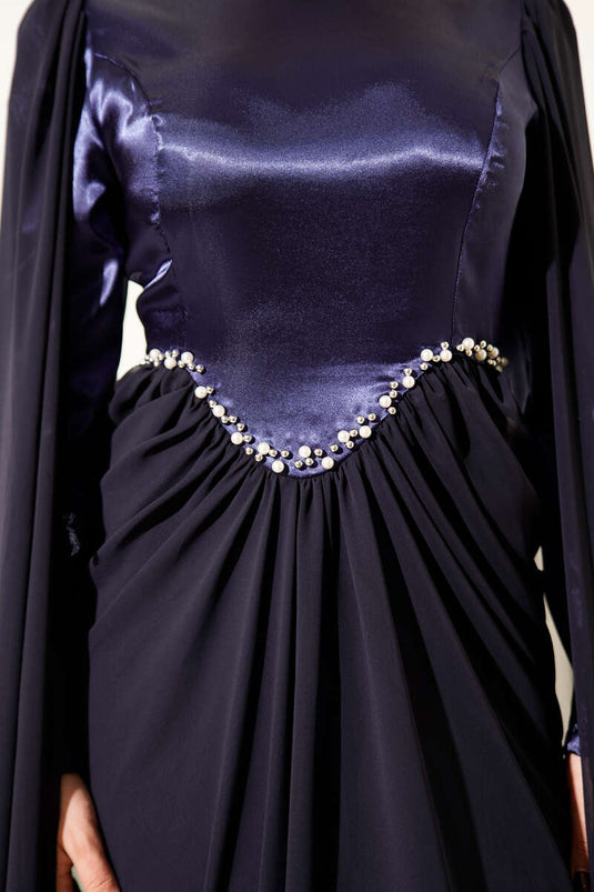 Marineblauwe avondjurk met schoudercape en details van steentjes.