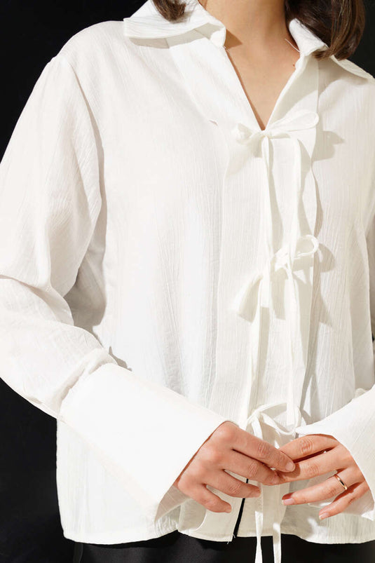 بلوزة بيضاء مع تفاصيل دانتيل في الأمام