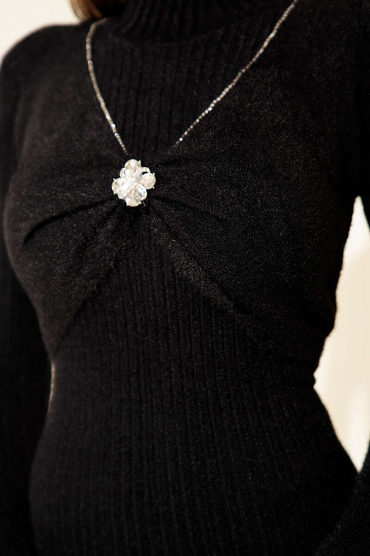 فستان أسود مزين بتفاصيل حجرية في الأمام وتصميم ملتحي