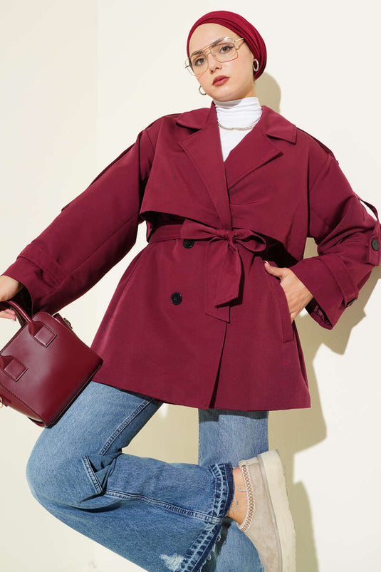 Trench-coat court bordeaux avec cape et ceinture.