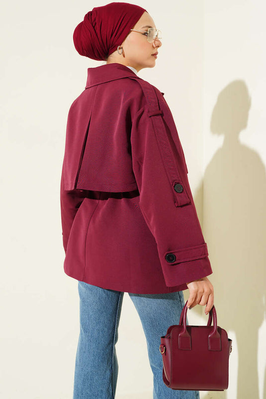 Trench-coat court bordeaux avec cape et ceinture.