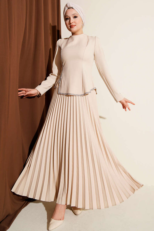 بدلة من قطعتين بتفاصيل حجرية وتنورة مطوية باللون البيج