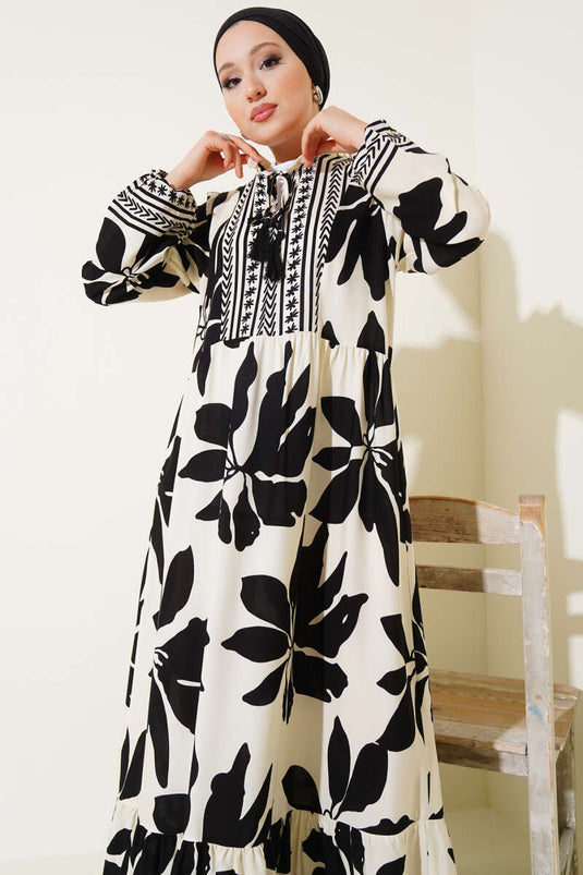 Zwarte jurk met patroon, rucheskraag en vetersluiting.