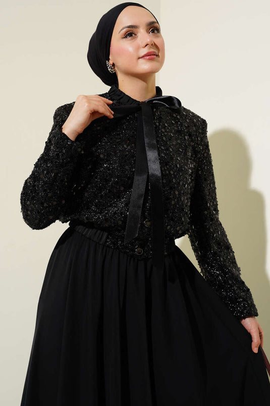 Met pailletten versierd tweedelig pak met kraag en lint, zwart