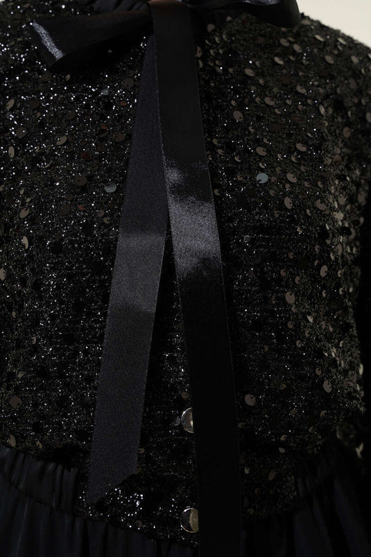 Met pailletten versierd tweedelig pak met kraag en lint, zwart
