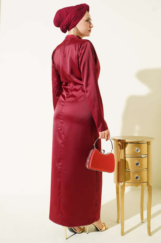 فستان سهرة ساتان عنابي مزين بطيات ذهبية ومشبك ذهبي