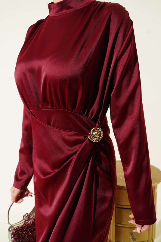 فستان سهرة ساتان عنابي مزين بطيات ذهبية ومشبك ذهبي