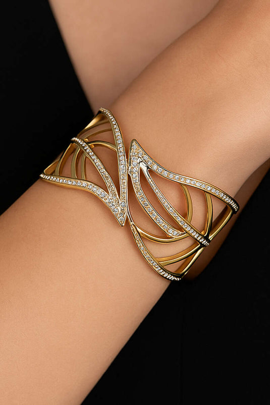 Gouden brede armband met bladmotief en steentjes.