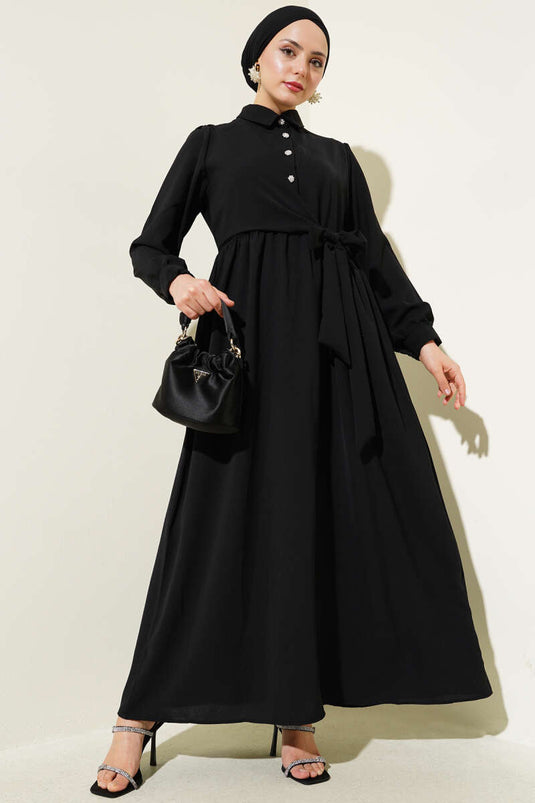 فستان أسود برباط جانبي وأزرار نصف حجر