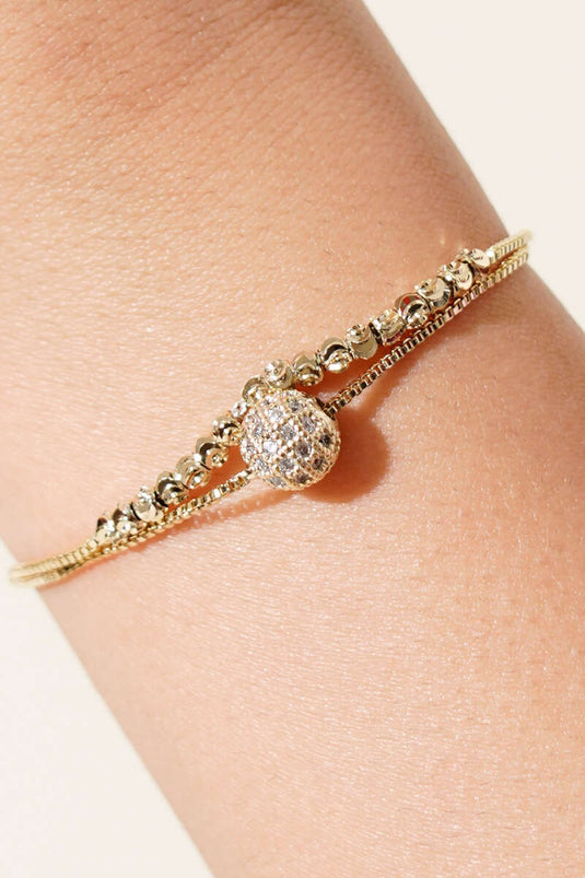 Pulsera dorada con detalles de piedras y bola