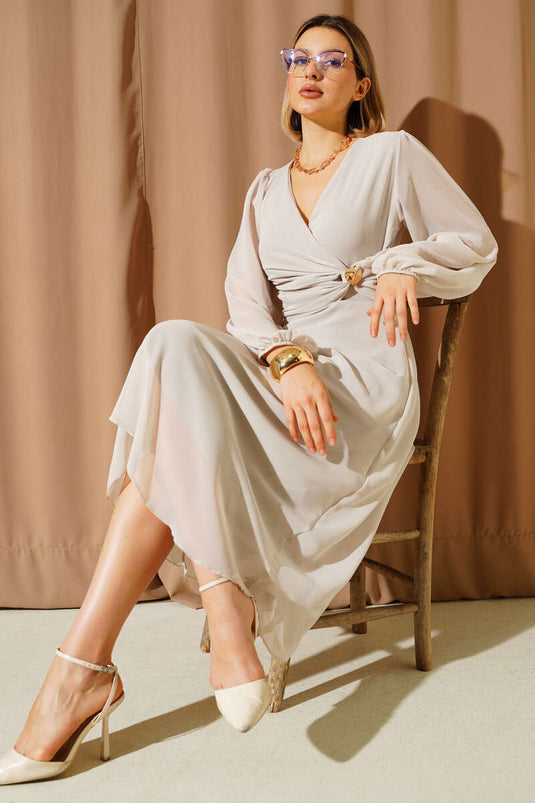 Jurk met V-hals en bronchdetails, versierd met steentjes.