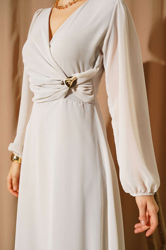 Jurk met V-hals en bronchdetails, versierd met steentjes.