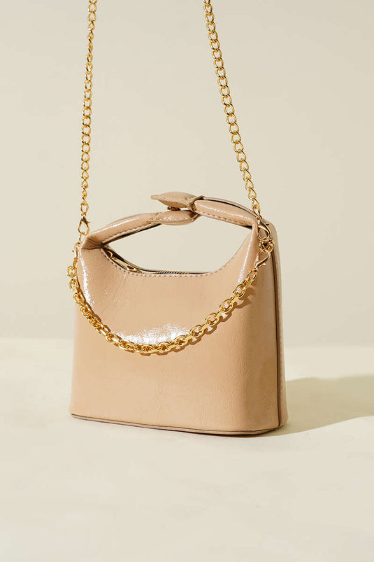 Bolso de charol con correa de cadena y asa a presión en color beige