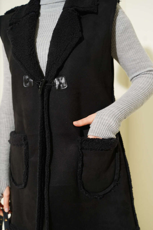 Gilet en daim noir, doublé de fourrure et doté de poches.