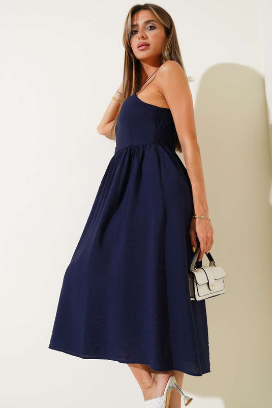 فستان فضفاض ذو حمالات رفيعة باللون الأزرق الداكن.