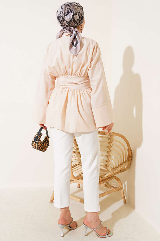 Tunique beige à ceinture intégrée et froncée sur le devant.