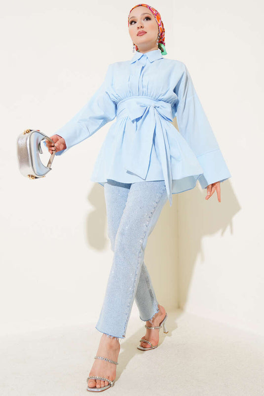 Tunique bleue à ceinture intégrée et froncée sur le devant.